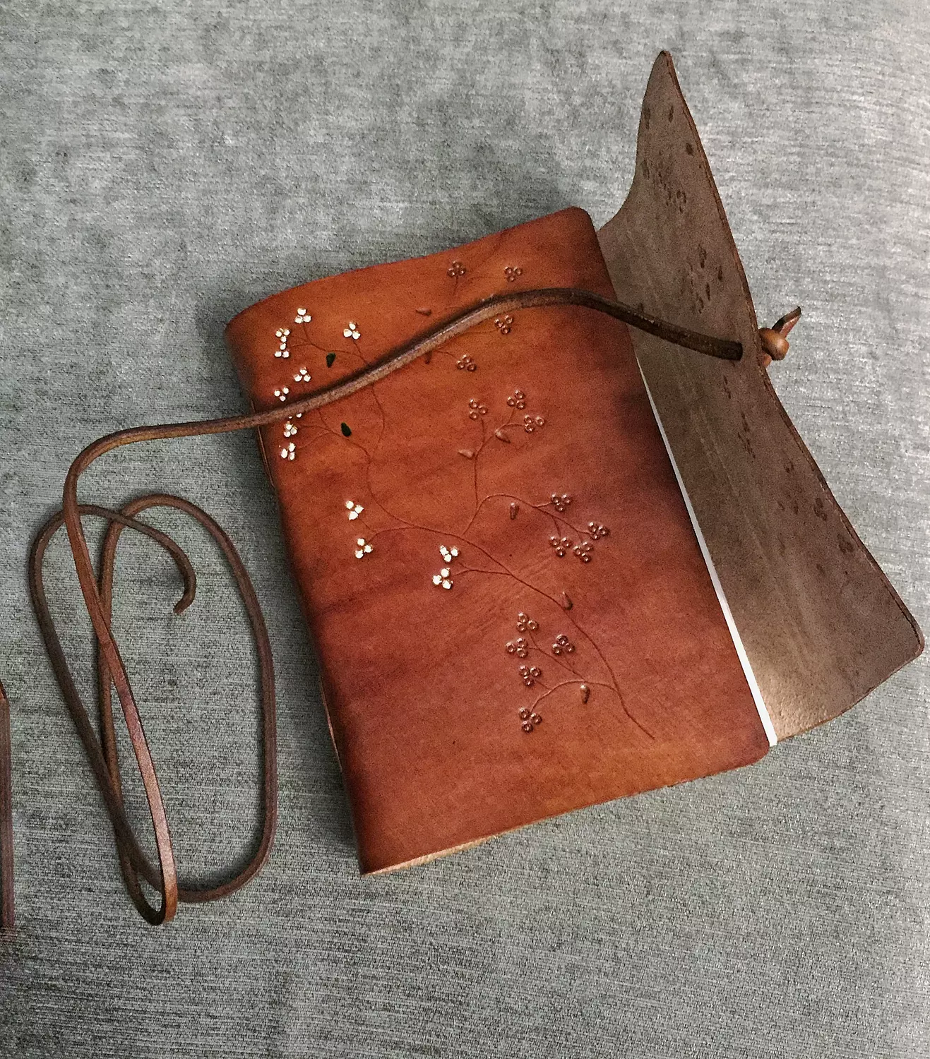 Tooled painted blossom vines leather journal with wraparound tie strap hover image